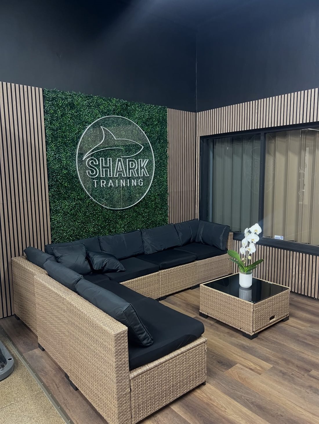 Shark Training lounge with the logo on a green living wall